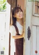 A young woman standing in front of a wooden door.