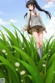 A girl in a school uniform walking through tall grass.