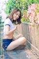 A woman sitting on the ground next to a wooden fence.