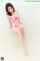 A woman in a pink bikini sitting in the water.