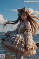 A woman in a dress standing on a rock by the ocean.