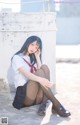 A woman in a school uniform sitting on the ground.