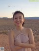 A woman in a pink dress standing in the desert.