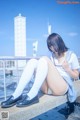 A woman sitting on a ledge with her legs crossed.