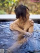 A woman sitting in a pool of water with her hands on her chest.